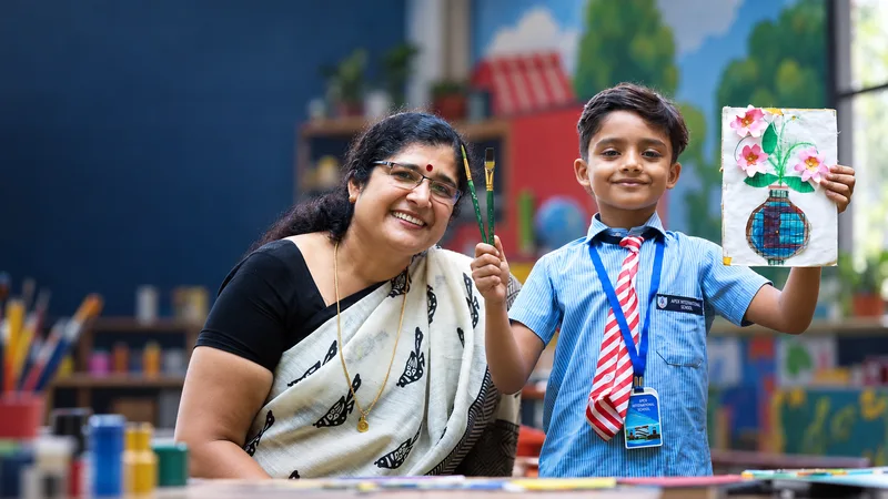 An Apex pupil and teacher proudly displaying a handmade flower artwork in the art classroom