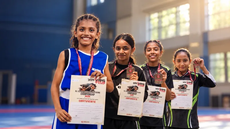 Four Apex kickboxing medallists proudly holding their medals and certificates