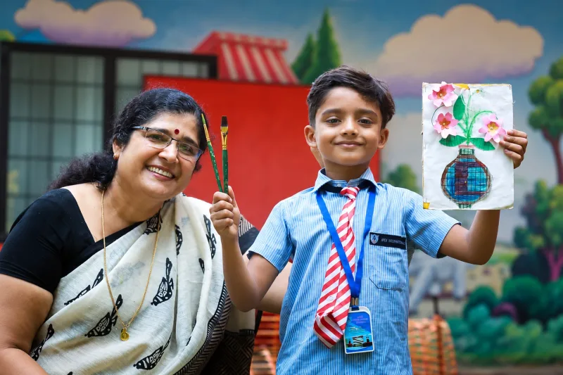 A pupil and teacher displaying a handmade flower artwork at Apex